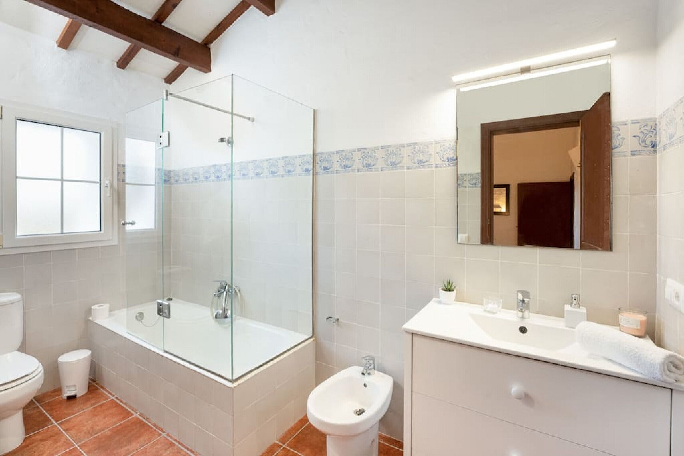 A bathroom with a glass-enclosed shower, a toilet, a bidet, a sink, and a mirror.