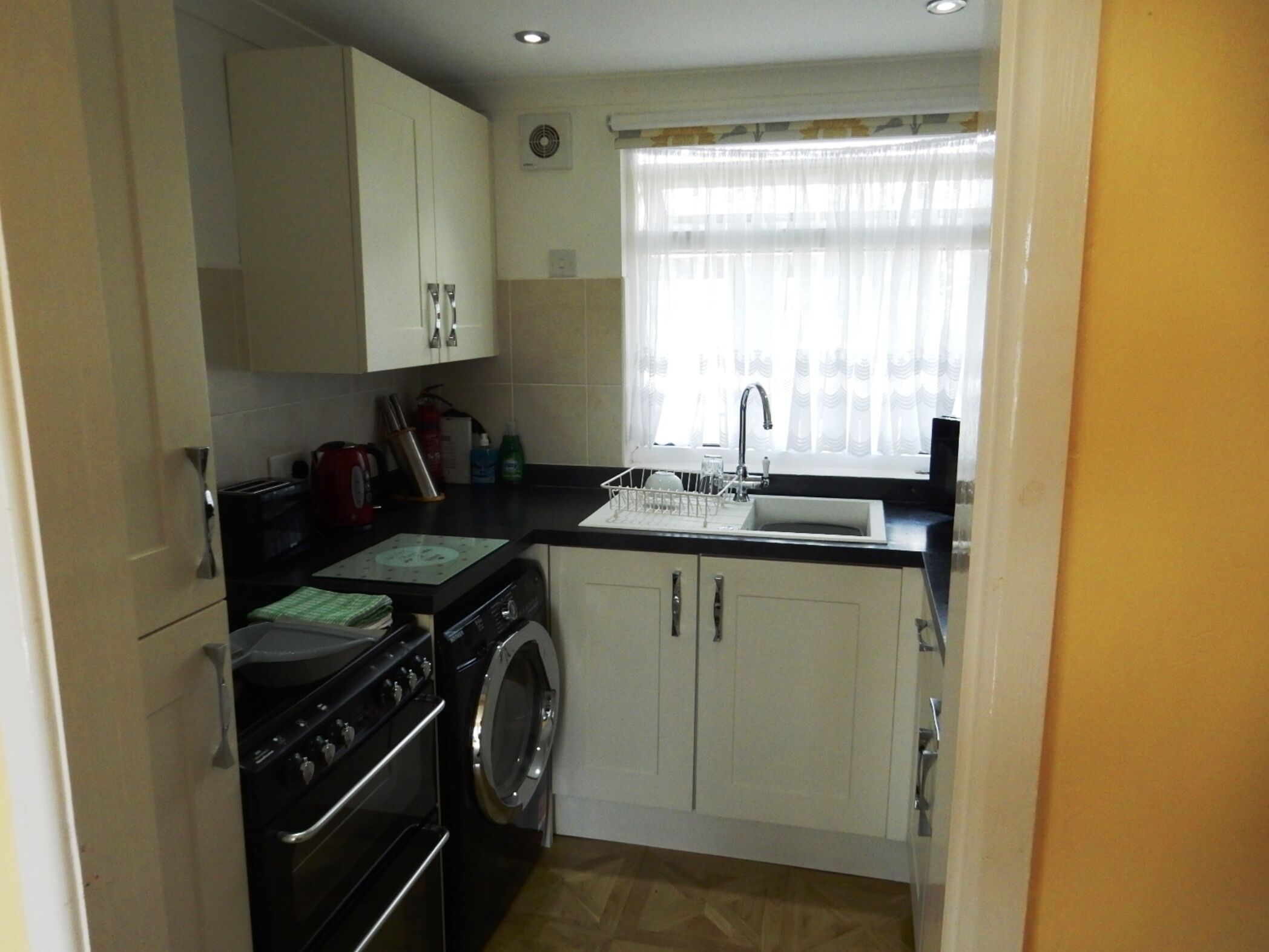 A compact kitchen with a washing machine, a stove, and a sink.