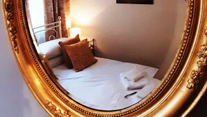 Ein Zimmer mit einem Bett, einem kleinen Nachttisch und einer Wandleuchte.
