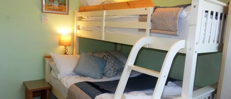 A bunk bed room with a small bedside table and a wall-mounted lamp.