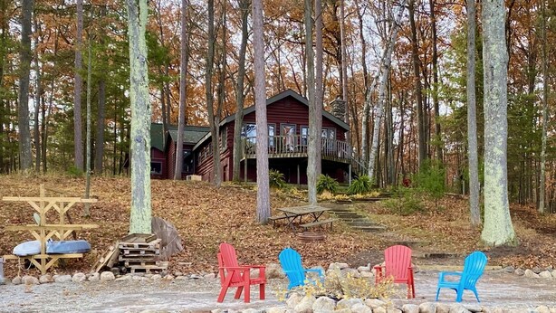 A cabin surrounded by trees, with a stone wall and a pond in the foreground. - Traverse City @ Rennie Lake  .. Idyllic Lakefront Retreat ..  CC49 ... Perfect! (traverse city)