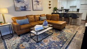 Ein Wohnzimmer mit braunem Ledersofa, einem Couchtisch und einem gemusterten Teppich.