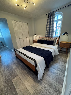A bedroom with a bed, bedside tables, a wardrobe, and a window with curtains.
