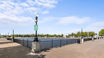 Paseo marítimo con un letrero de prohibición de fumar, un farol y una valla metálica.