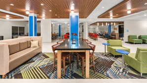 A modern lounge area with a long table, comfortable seating, and a patterned carpet. - Holiday Inn Express & Suites Suisun City by IHG (Suisun City)