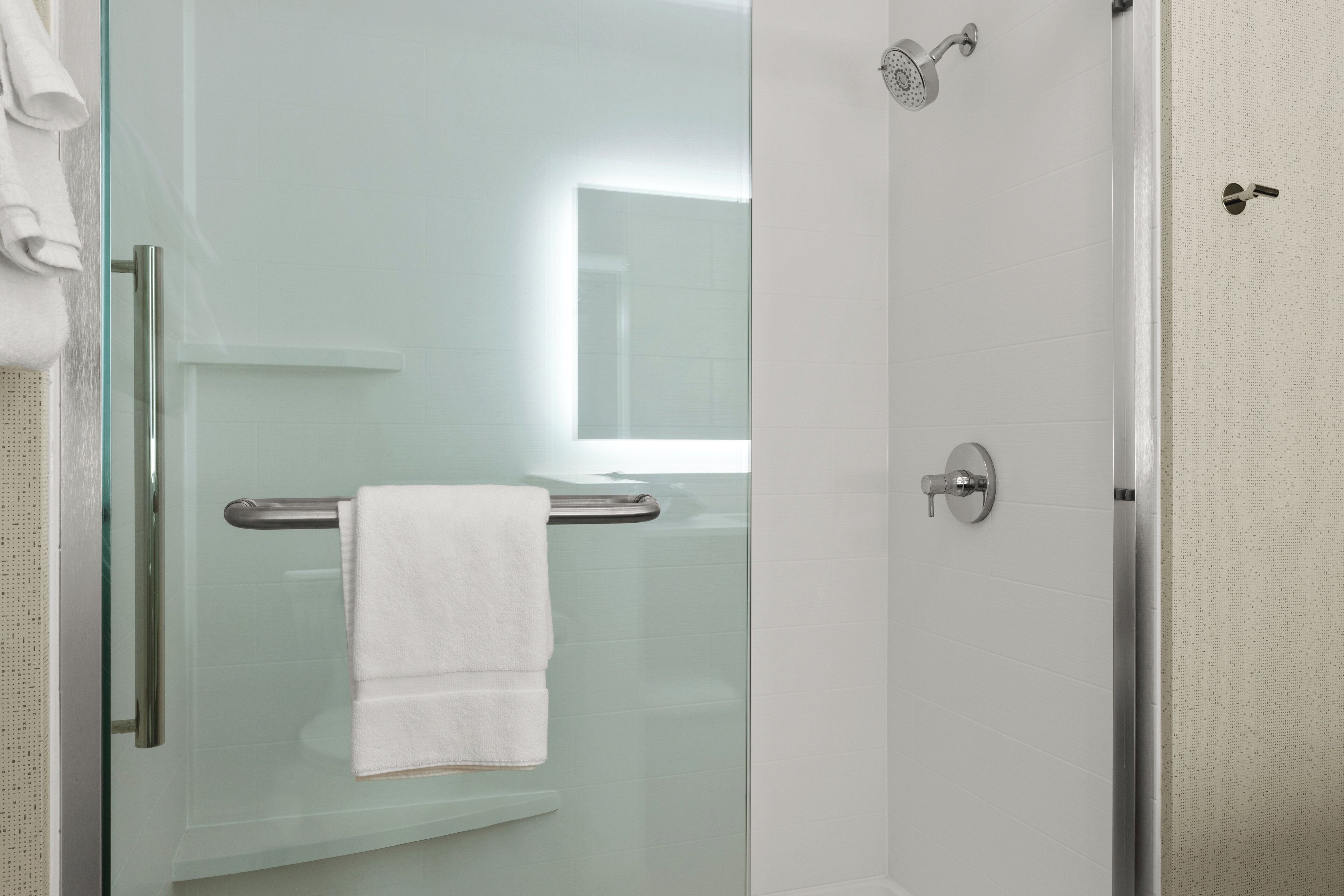 A modern bathroom with a glass shower enclosure, a towel rack, and a visible showerhead.