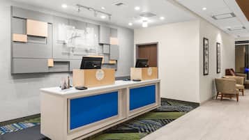 A reception area with a modern design, featuring a reception desk, seating area, and a wall-mounted display.