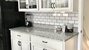 Eine Küche mit weißen Schränken, Granit-Arbeitsplatten und einem schwarzen Kühlschrank.