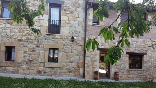 A stone building with multiple windows, a door, and a small porch area. - Place of peace. (Arroyo de Valdearroyo)