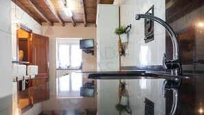 A kitchen with a reflective backsplash, wooden ceiling beams, and a modern faucet. - Place of peace. (Arroyo de Valdearroyo)
