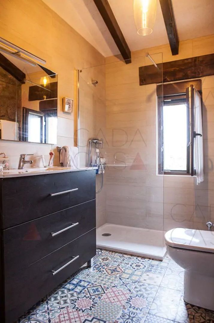 Un baño con tocador oscuro, ducha e inodoro.
