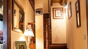 A wooden staircase with a handrail, a wall-mounted picture frame, and a table with a lamp and picture frame. - Place of peace. (Arroyo de Valdearroyo)