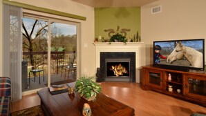 A living room with a fireplace, a television, and a view of the outdoors. - Cedar Lodge 204 (Pigeon Forge)