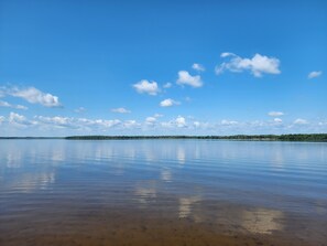 Un lago tranquilo con cielo despejado y orilla distante.