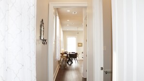 A hallway with a dining area at the end, featuring a table and chairs. - Elegant Historic 1906 2BR • Balcony • Lower Garden District (New Orleans)