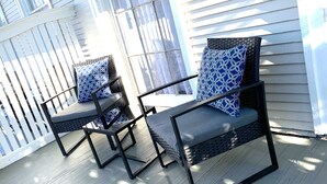 Two black wicker chairs with blue patterned cushions on a wooden deck. - Elegant Historic 1906 2BR • Balcony • Lower Garden District (New Orleans)