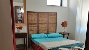 A bedroom with a bed, a bedside table, a mirror, and a window with curtains. - Villa Camilla Guest House - Appartamento 1 (Reggio Calabria)