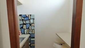 A narrow kitchen with a tiled backsplash, a sink, and a stool. - Villa Camilla Guest House - Appartamento 1 (Reggio Calabria)