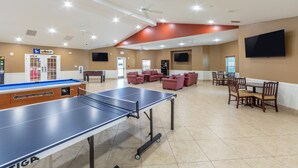 Un espacio interior amplio con mesa de ping pong, asientos y televisor.