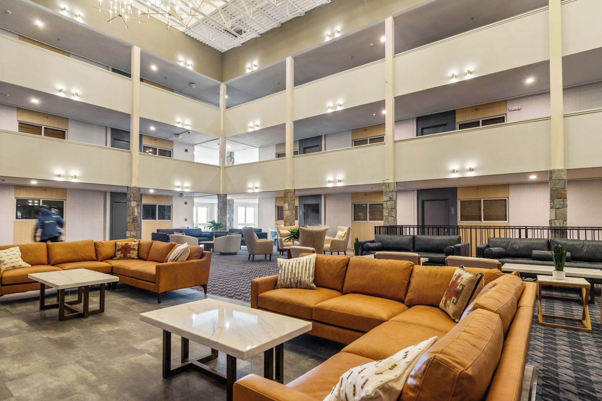Um hall amplo com várias áreas de estar, teto alto com iluminação e design arquitetônico moderno.