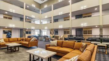 Um hall amplo com várias áreas de estar, teto alto com iluminação e design arquitetônico moderno.