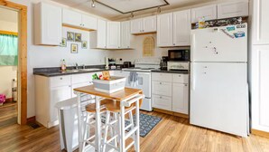 A kitchen with white cabinets, a wooden countertop, a refrigerator, and a microwave.