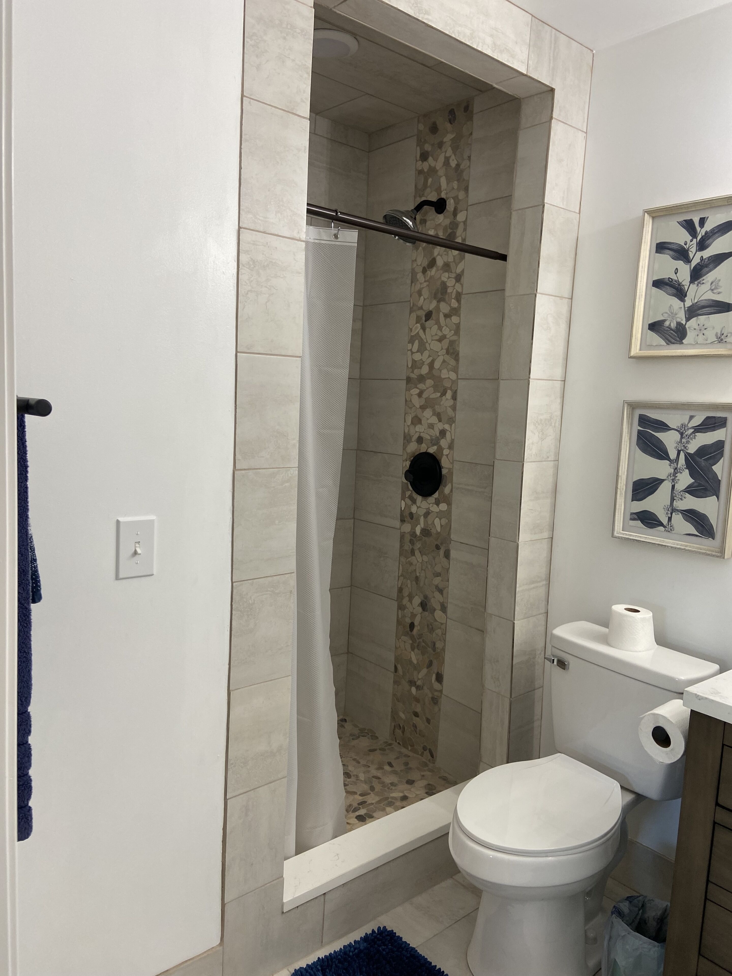 Un baño con ducha, inodoro y perchero para toallas.