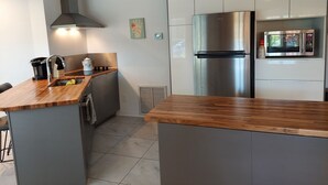 Une cuisine moderne équipée d’un réfrigérateur en acier inoxydable, d’un four à micro-ondes et d’un plan de travail en bois.