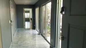 Un couloir doté d’un sol en marbre, de grandes fenêtres et d’une porte située sur le côté droit.