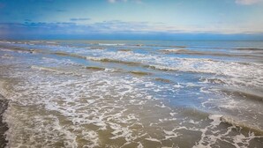 Una playa con olas suaves lamiendo la orilla.