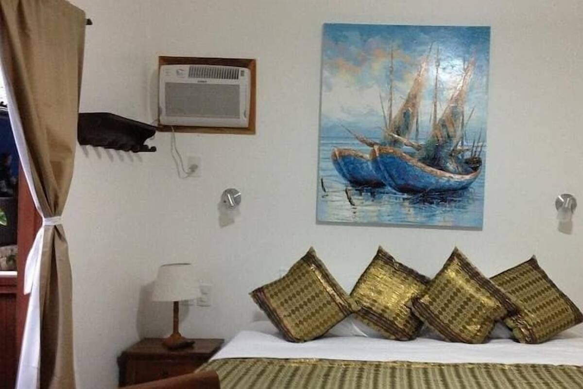 Ein Schlafzimmer mit einem Bett, einem Bild eines Bootes, einer Klimaanlage und einer Lampe.