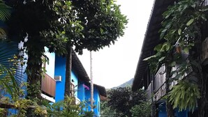 A courtyard with blue buildings, potted plants, and outdoor seating. - Pousada dos Meros (Angra dos Reis)