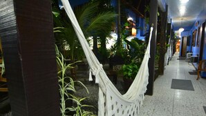 A hallway with a hammock, potted plants, and a tiled floor. - Pousada dos Meros (Angra dos Reis)