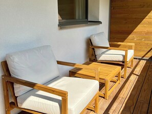A wooden deck with two wooden chairs and a small table, a window with a view of the sky, and a wooden floor. - Alte Gasse 9 Appartement/Fewo 4-Bettwohnung by Interhome (Engelberg)