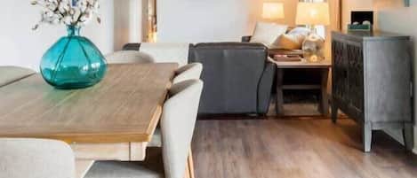 Un salon moderne comprenant un coin repas, un téléviseur à écran plat fixé au mur et un ensemble de canapés.
