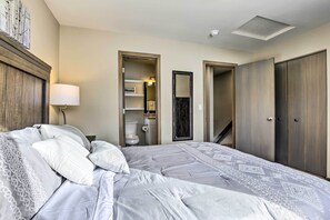 Et hotelværelse med en stor seng, en sengetabletlampe, et klædeskab og et badeværelse, der kan ses gennem en åben dør.