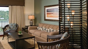 A cozy living area with a sofa, two chairs, a coffee table, a lamp, and a framed picture on the wall.