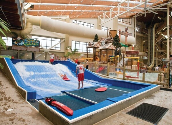 Ein Indoor-Wasserpark mit einer Wellenbad, Rutschen und einer hölzernen Spielanlage.