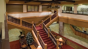 A grand staircase with a red carpet, wooden railings, and a chandelier.