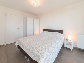 A bedroom with a bed, a nightstand, a lamp, and a wardrobe.