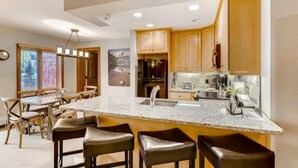 A modern kitchen with wooden cabinets, a marble countertop, and a built-in oven. - Ski in, Ski out 3 Bedroom Mountain Residence in the Heart of Lionshead Village with Heated Slope Side Pool and Hot Tub (Vail)