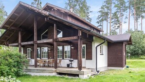 A two-story wooden house with a balcony, large windows, and a grassy yard. - Tahkon rummikub by Interhome (Nilsiä)