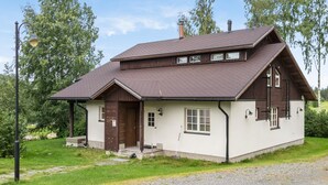 A two-story house with a sloped roof, a front porch, and a chimney. - Tahkon rummikub by Interhome (Nilsiä)