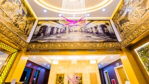 A grand lobby with a large chandelier, ornate murals, and a central floral arrangement. - Sakura Hotel (Hoa Binh)