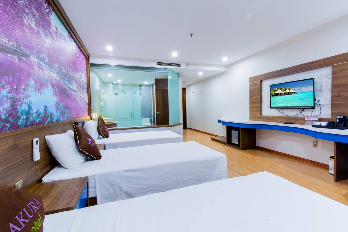 A hotel room with two beds, a TV, and a large window.