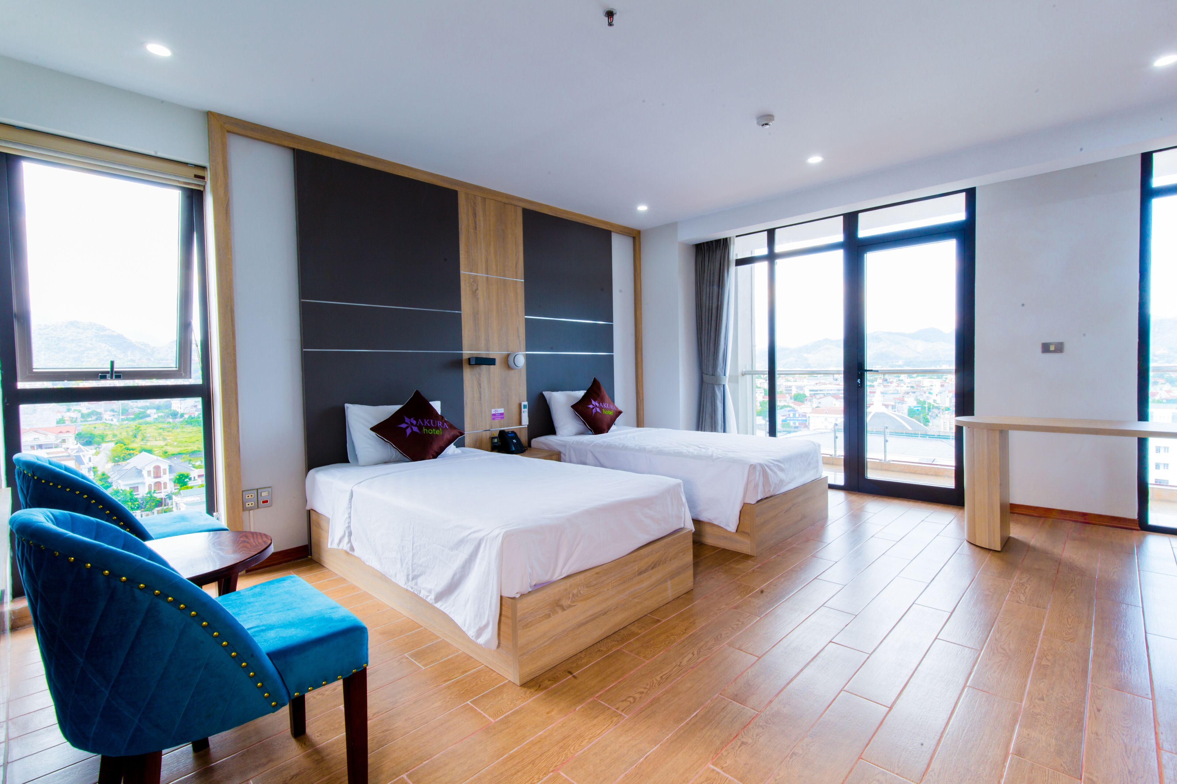Una habitación de hotel con dos camas, un ventanal grande y vistas a la ciudad.