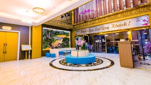 A lobby with a marble floor, a reception desk, and a seating area with blue cushions. - Sakura Hotel (Hoa Binh)