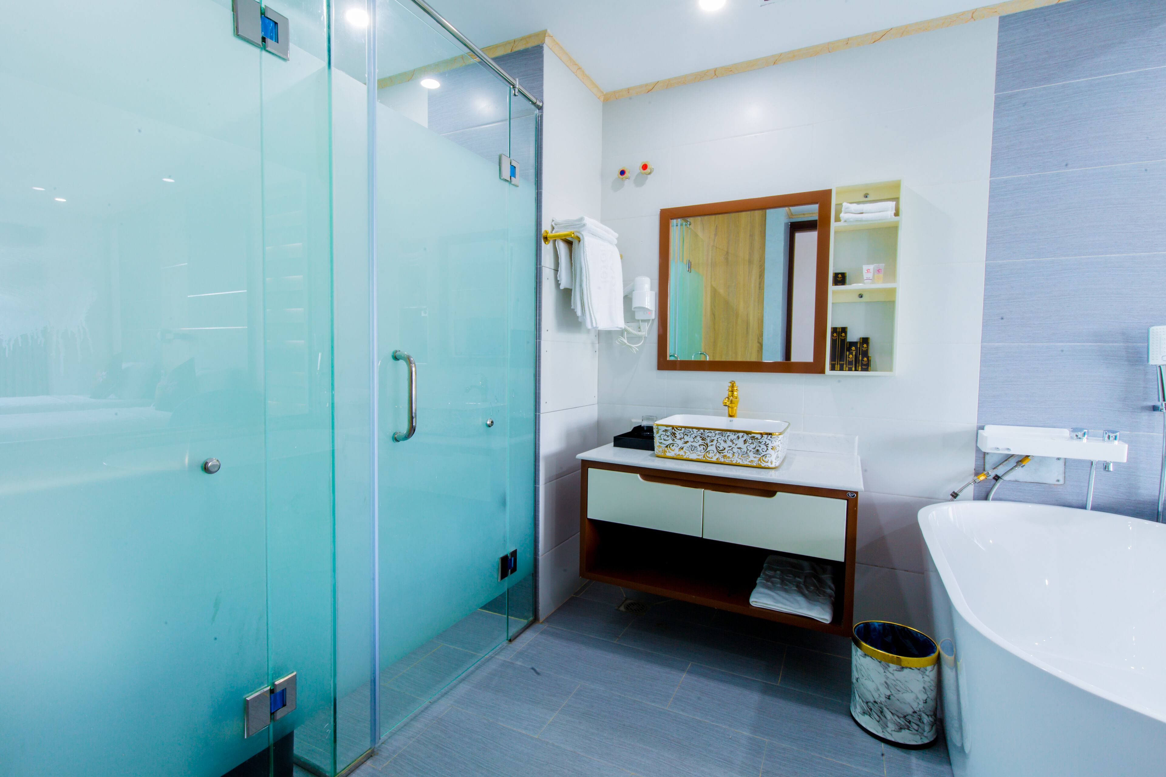 A modern bathroom with a glass shower enclosure, a white sink with a marble countertop, and a large bathtub.