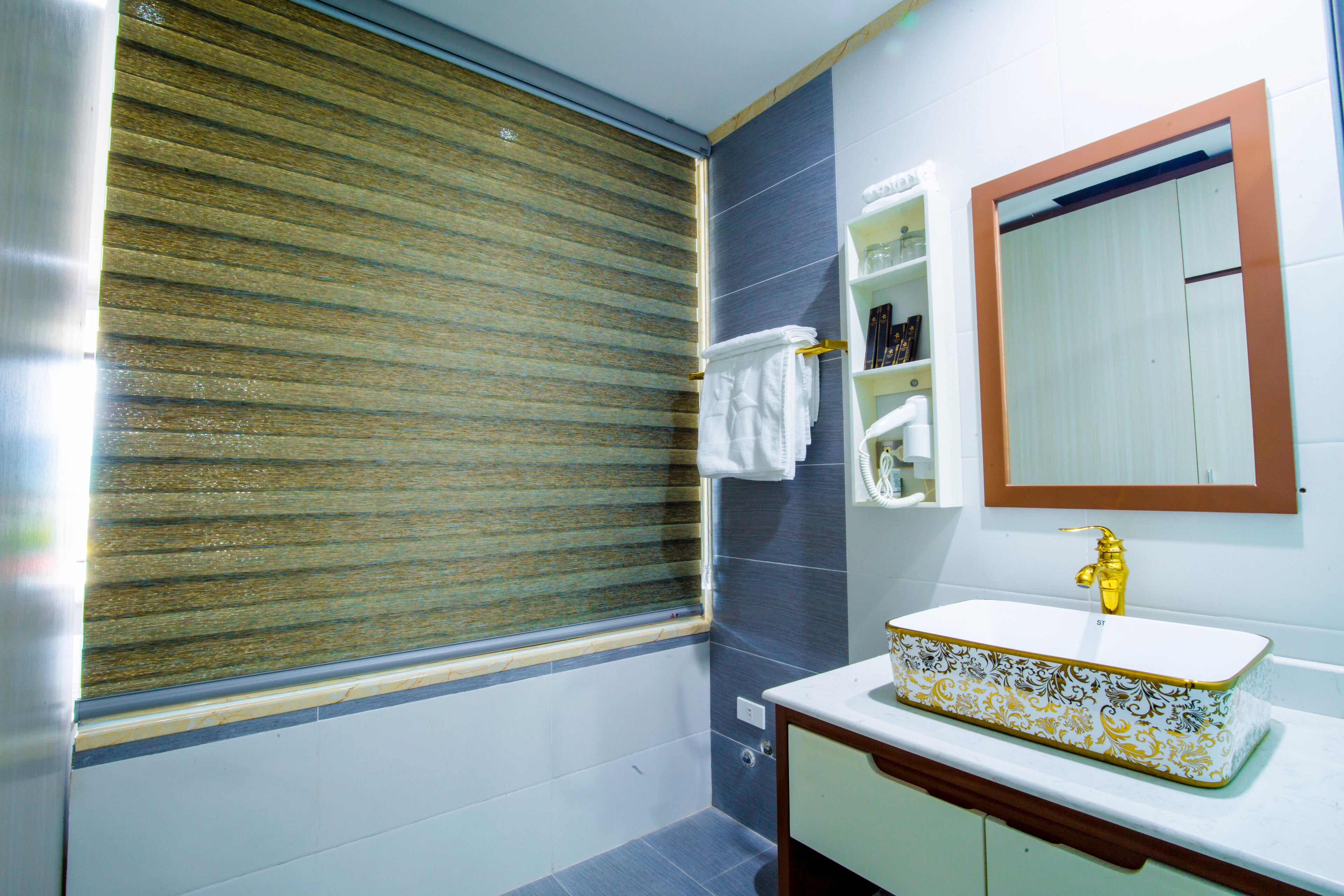 Un baño con lavamanos blanco, un espejo y un perchero para toallas.