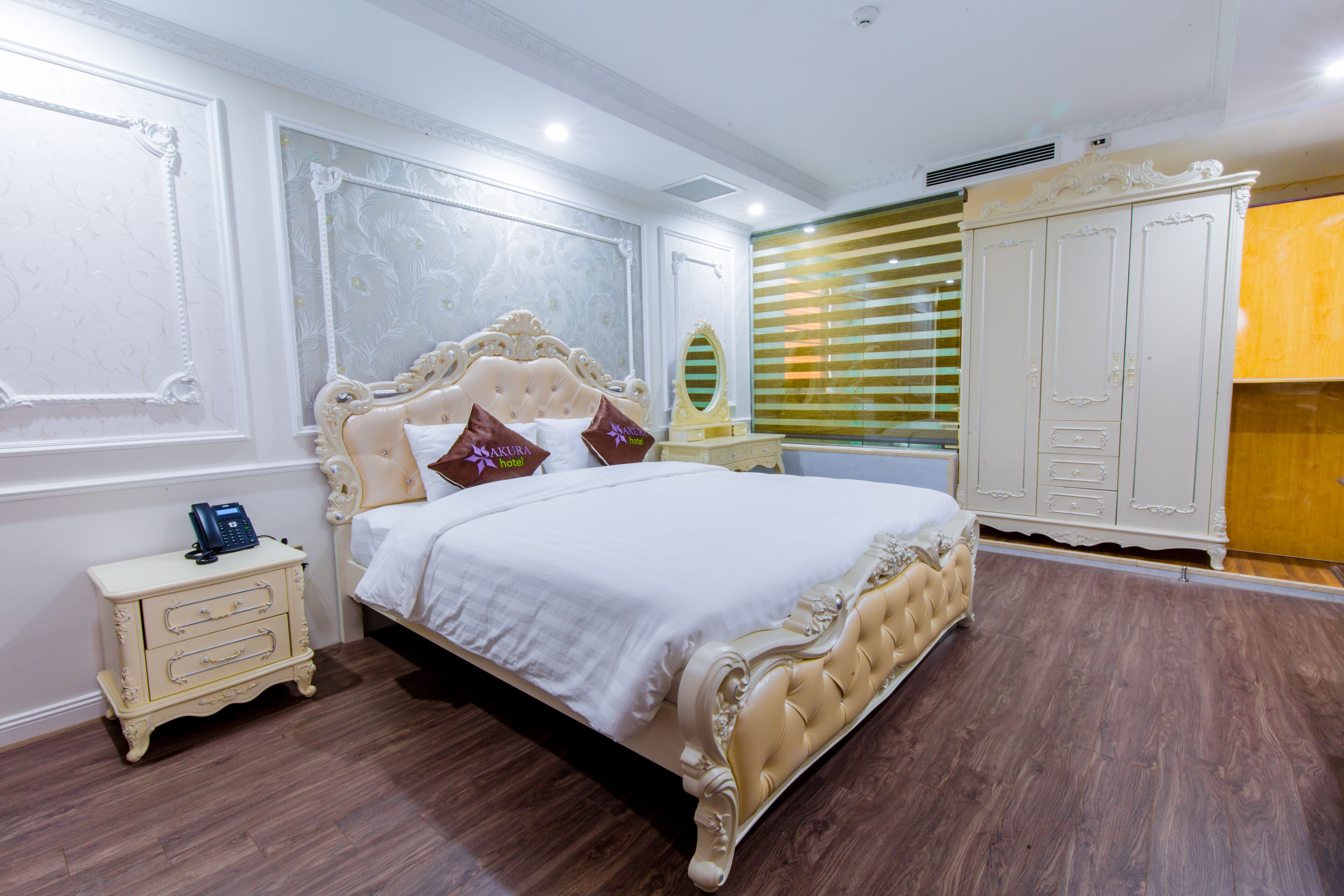 A bedroom with a large bed, a nightstand, a wardrobe, and a mirror.